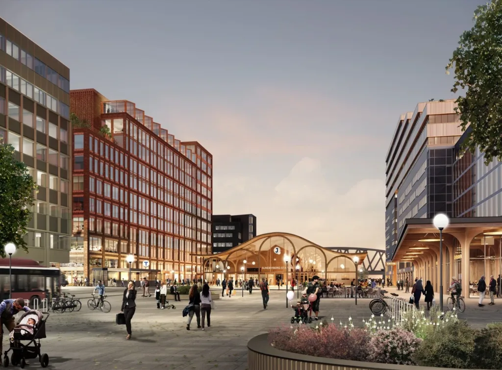 En öppen stadsplats med människor, moderna byggnader och en välvd träkonstruktion i mitten.