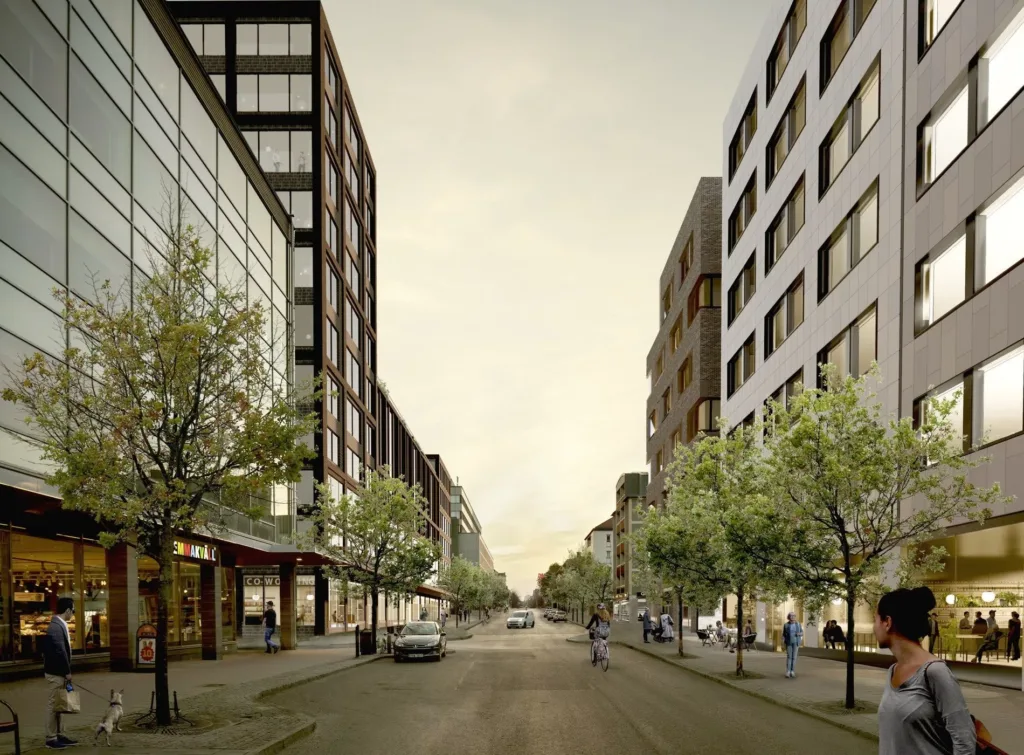 En livlig stadsgata omgiven av moderna byggnader med träd längs trottoarerna.