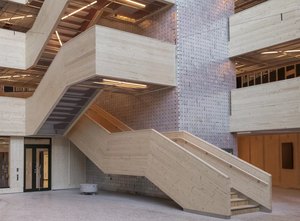 En ljus trappa av trä med flera nivåer, omgiven av tegelväggar och moderna detaljer.