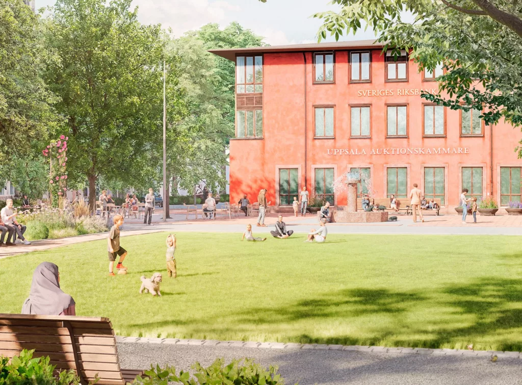 Närbild av samma park med människor som promenerar, sitter och leker nära en röd tegelbyggnad.