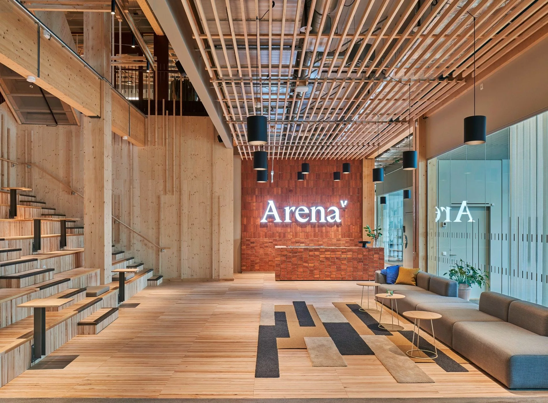 En elegant interiör med trädetaljer, tegelvägg och texten "Arena" synlig på väggen.