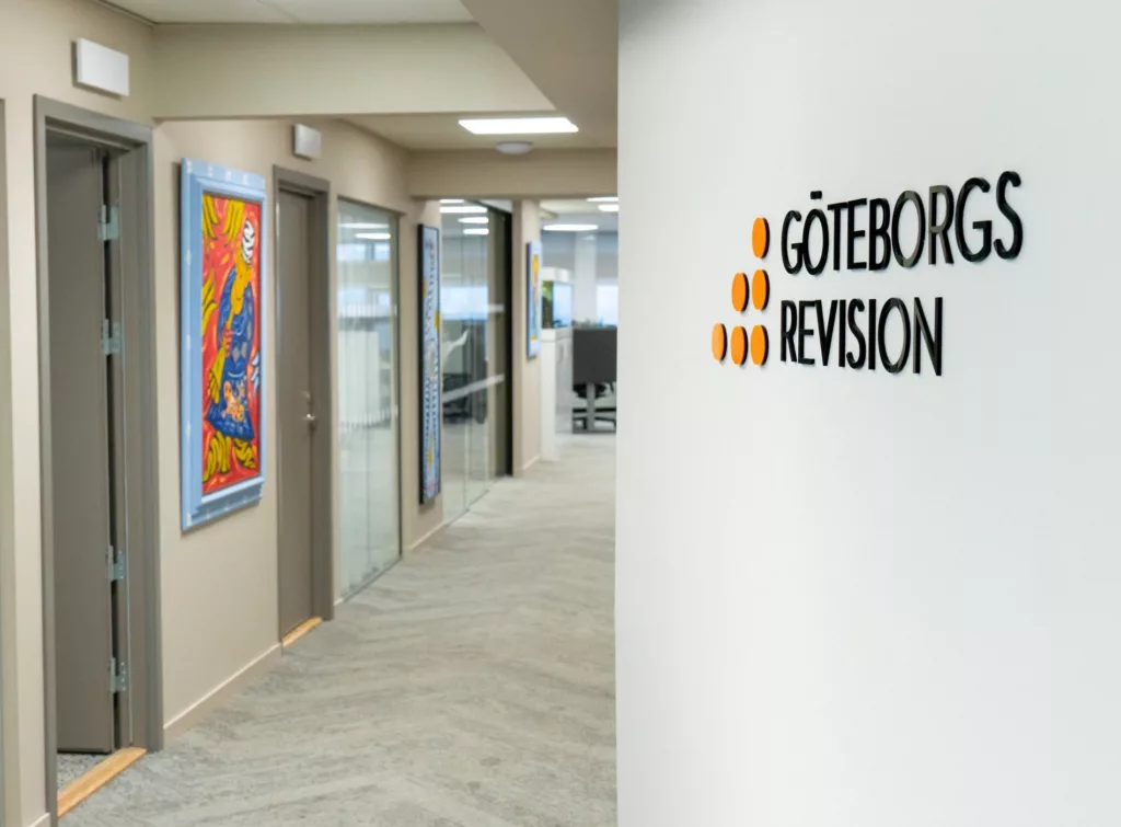 En hall med en logotyp på väggen som lyder "Göteborg Revision", kontorsdörrar och färgglad konst på vänster sida.
