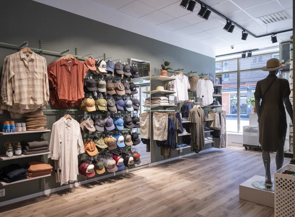 En butik med kläder, hattar och accessoarer organiserade på hyllor och klädställningar.
