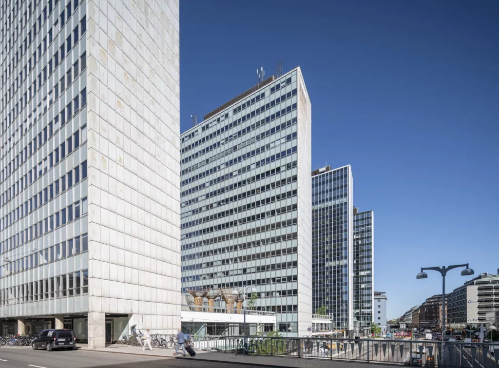 Höga moderna byggnader med stora glasfasader mot en blå himmel.