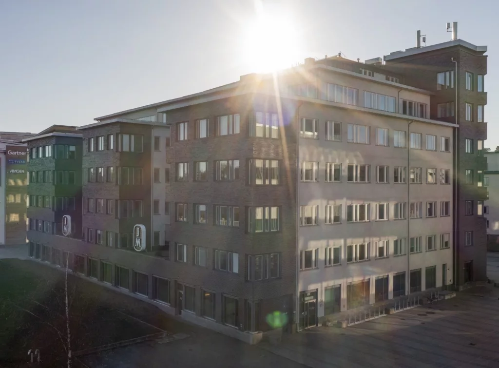 En modern byggnad med flera våningar badar i solljus, med solens strålar som lyser genom taket.