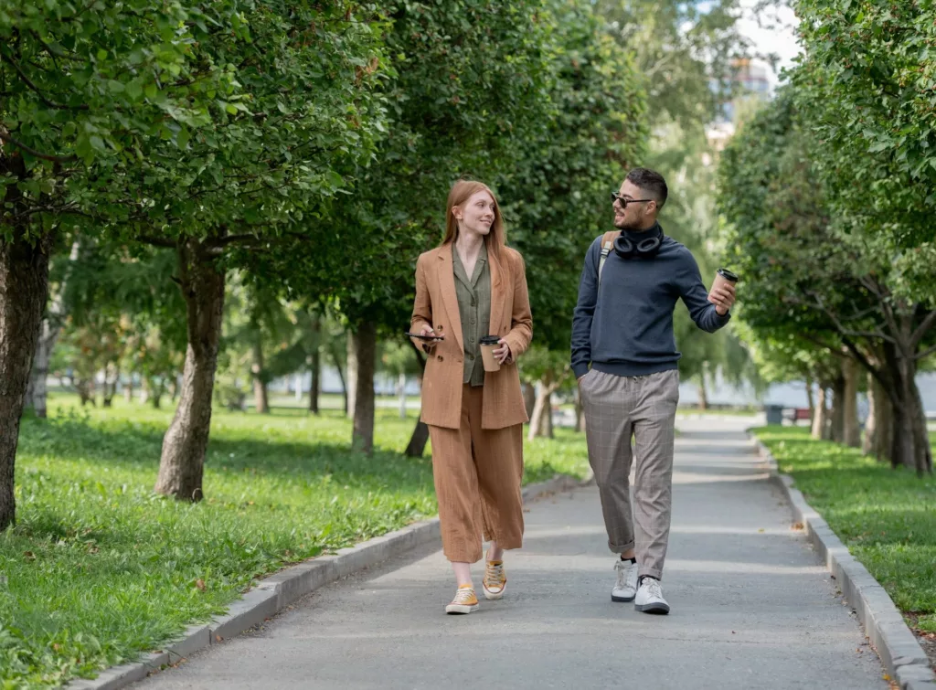 En man och en kvinna promenerar på en gångväg i en grön park.