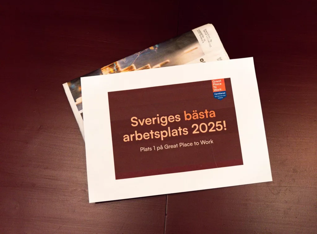 Ett papper på ett bord med texten "Sveriges bästa arbetsplats 2025! What I job Great Place to Work."