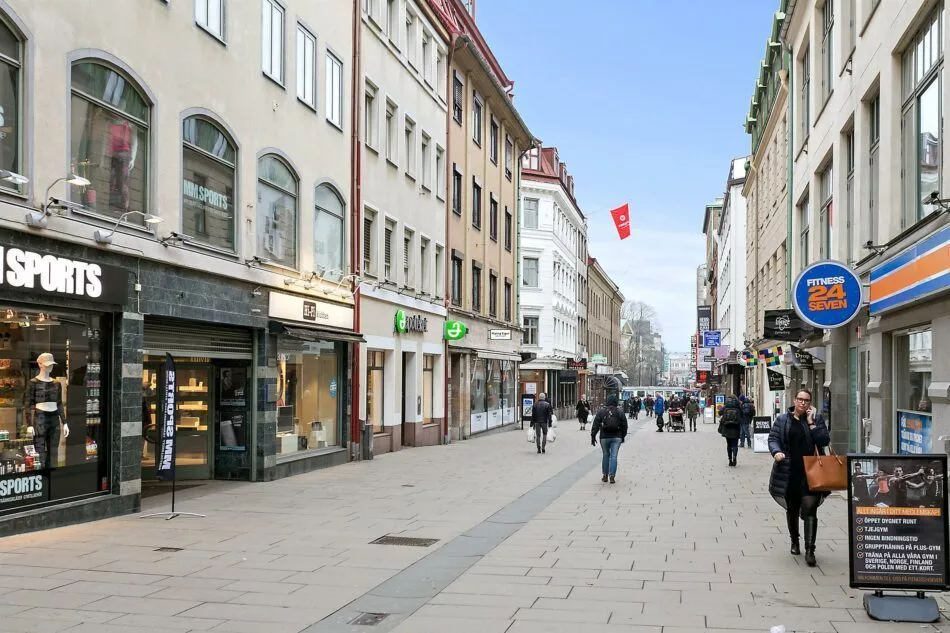En stadsgata med människor som promenerar och butiker längs sidorna.