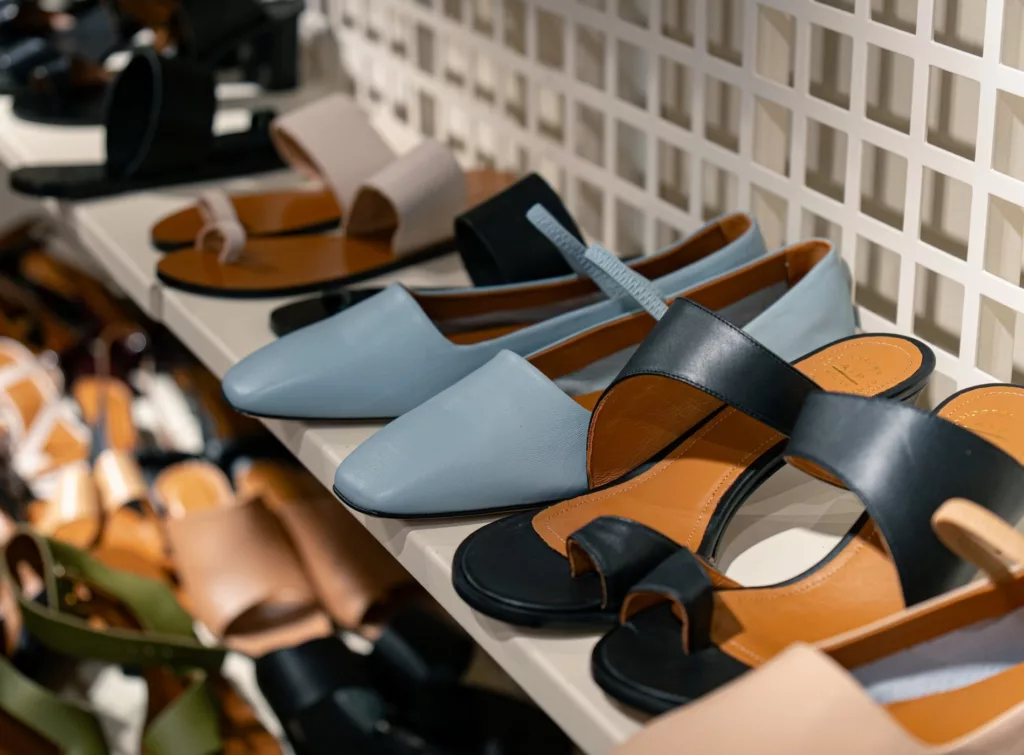 Hyllor med olika typer av skor, inklusive ljusblå flats och svarta sandaler.