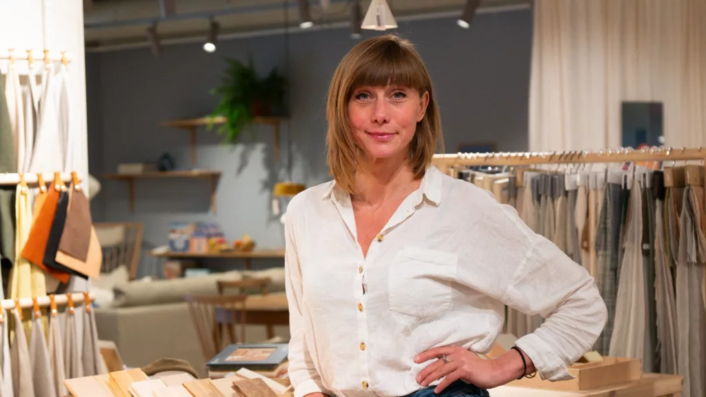 En kvinna i vit skjorta står framför hyllor i en butik.