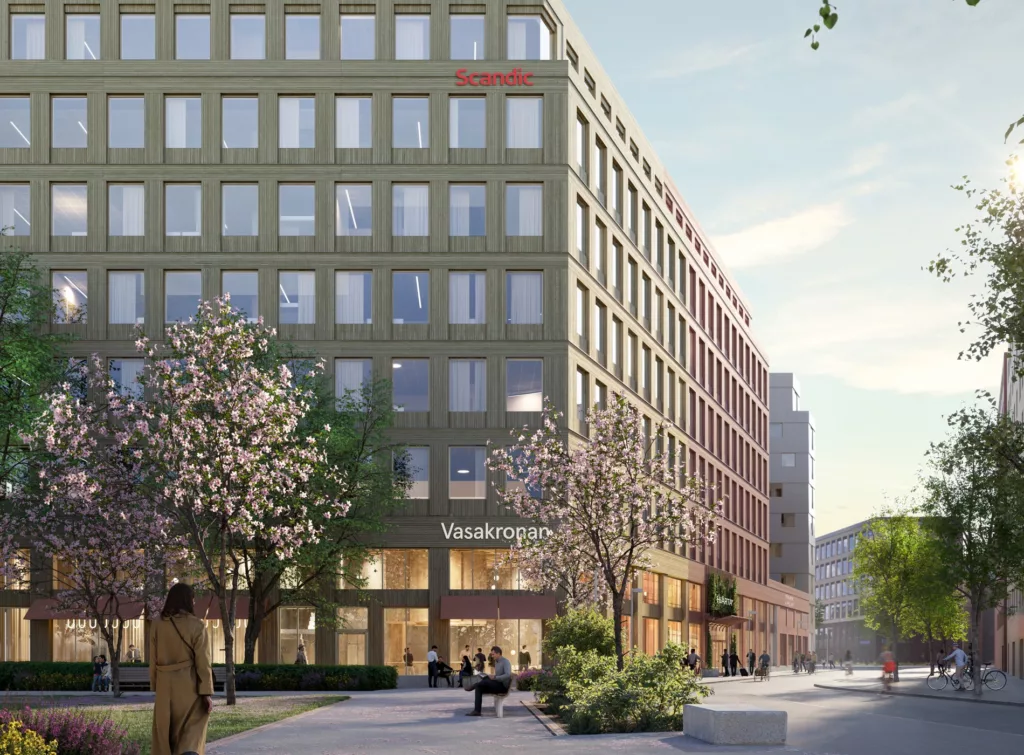 4. En grön kontorsbyggnad omgiven av träd och grönska, med texten "Vasakronan" synlig på fasaden och en gångväg i förgrunden.