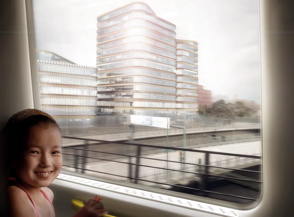 Ett barn som ler sitter vid ett fönster med en stadsmiljö och moderna byggnader i bakgrunden.