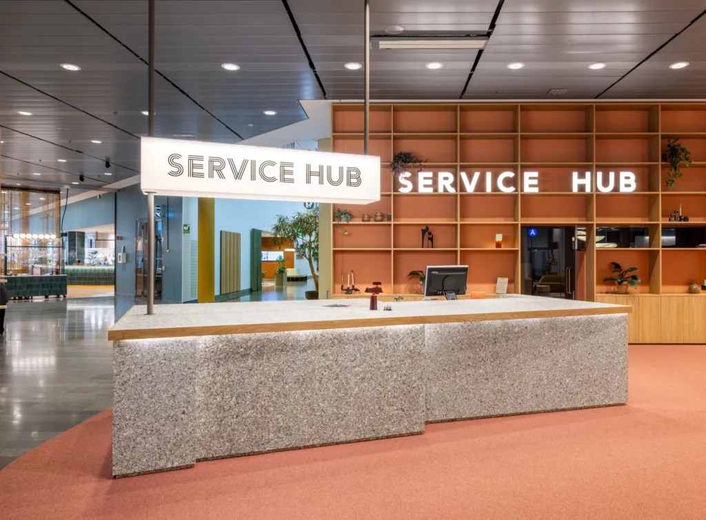 En receptionsdisk med skylten "SERVICE HUB" ovanför och en modern inredning.