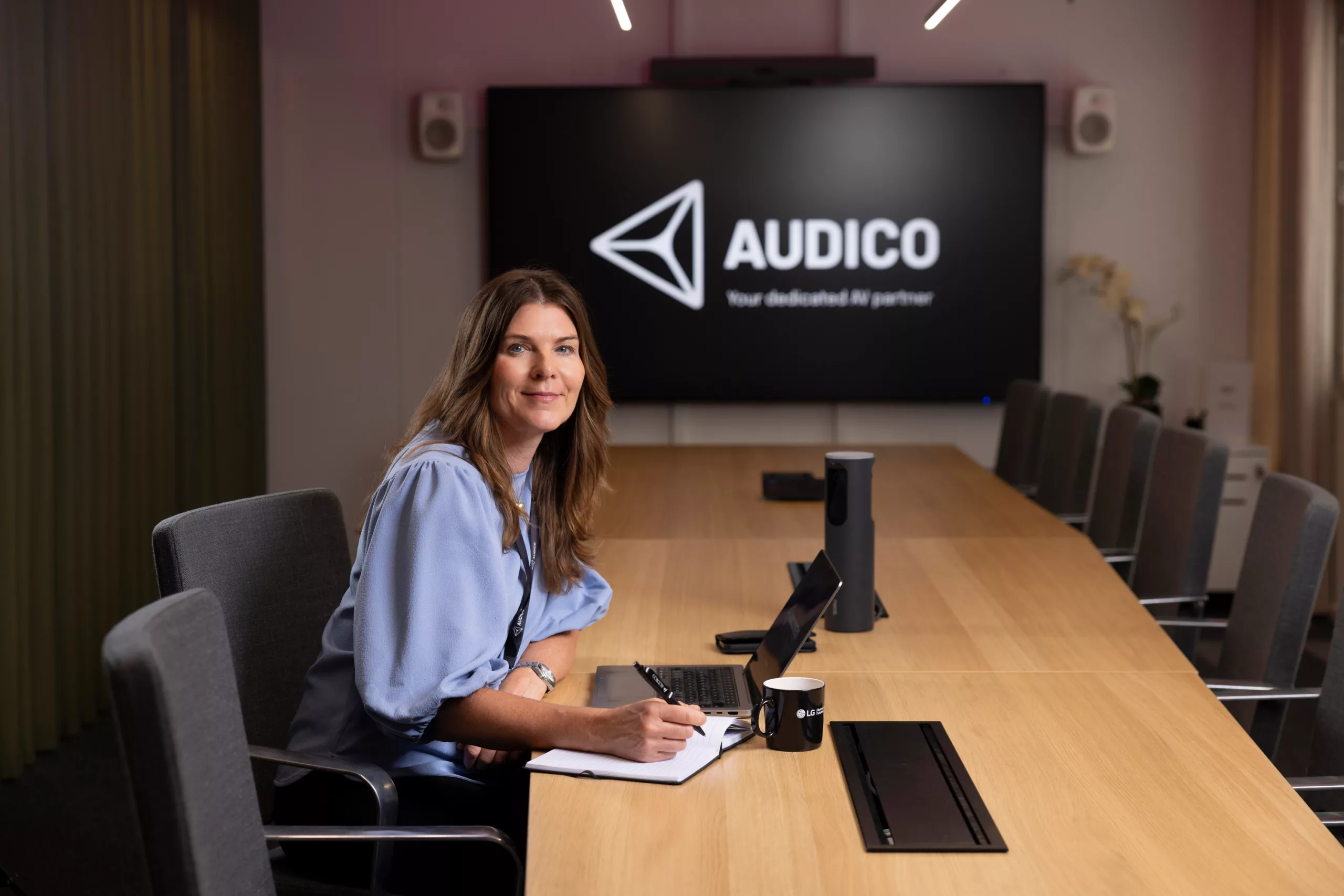 Johanna Berlinde, CEO på Audico i et mötesrum framför en digitalskärm.