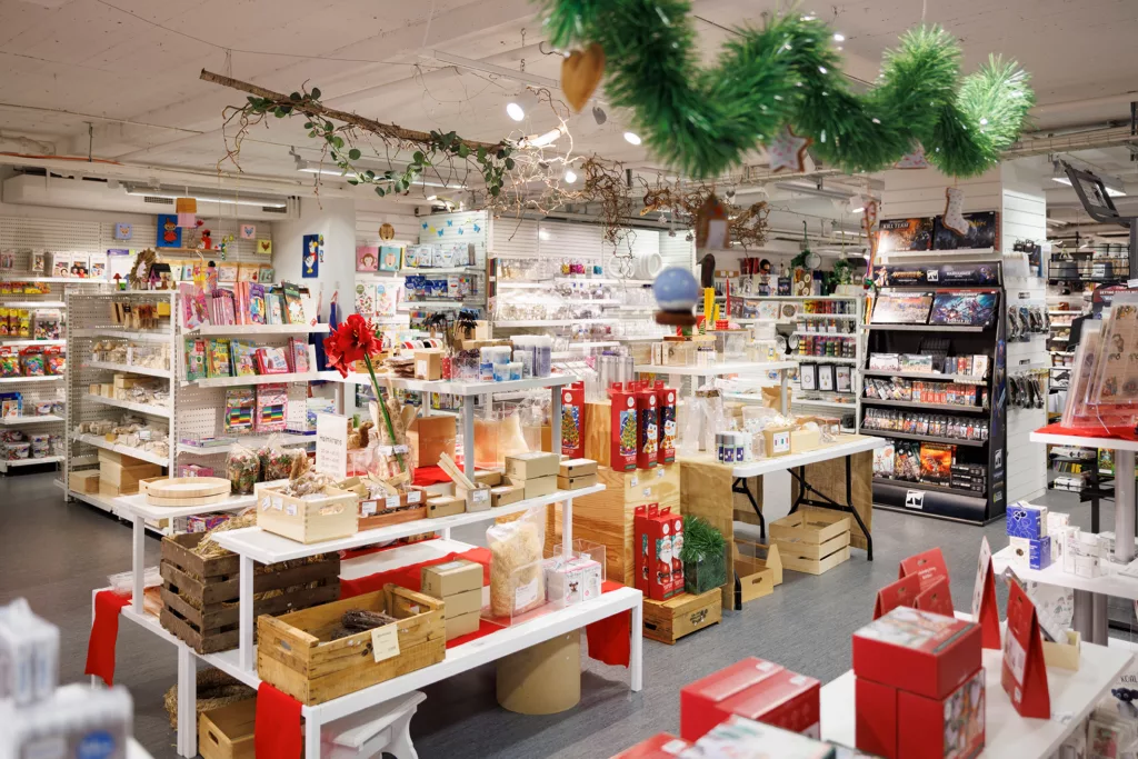 En butik fylld med juldekorationer, ljus, gåvor och grön girland hängande från taket.