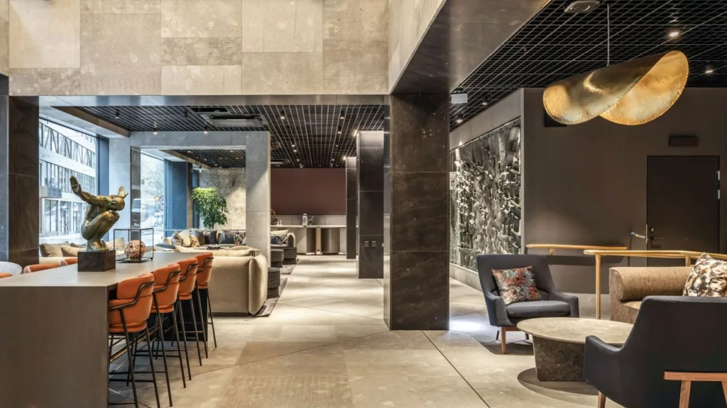 En stilfull lounge med barstolar, soffor och mörk inredning samt dekorativa väggdetaljer.