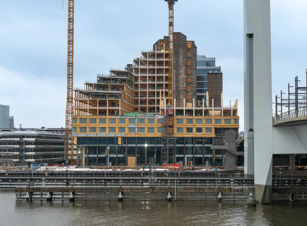 Byggarbetsplats med ett modernt hus under konstruktion, omgivet av två höga byggkranar.
