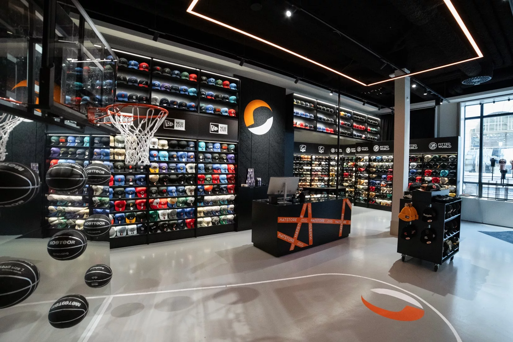 En butik med sportskor och utrustning, hyllor fyllda med färgglada skor och en basketkorg nära en disk.