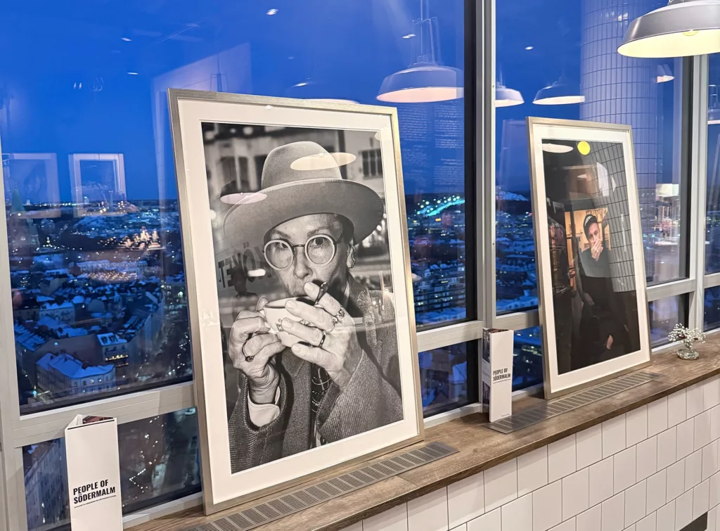 Inramade fotografier stående på en fönsterbräda med utsikt över en stad i skymning.