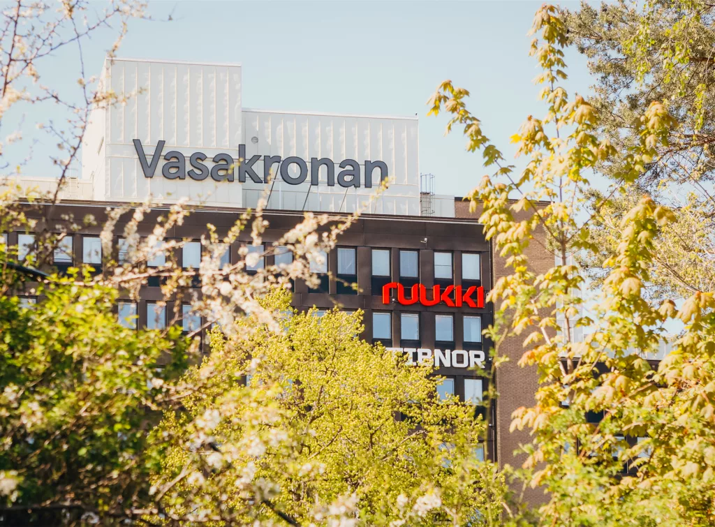 1. Kontorsbyggnad med Vasakronan och Avida-logotypen synliga bakom trädgrenar i förgrunden.