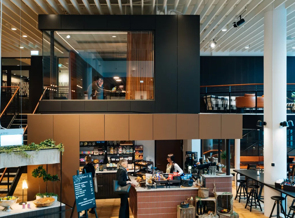 4. Ett modernt kafé med en barista som jobbar bakom disken och sittplatser på både nedre och övre våningen.