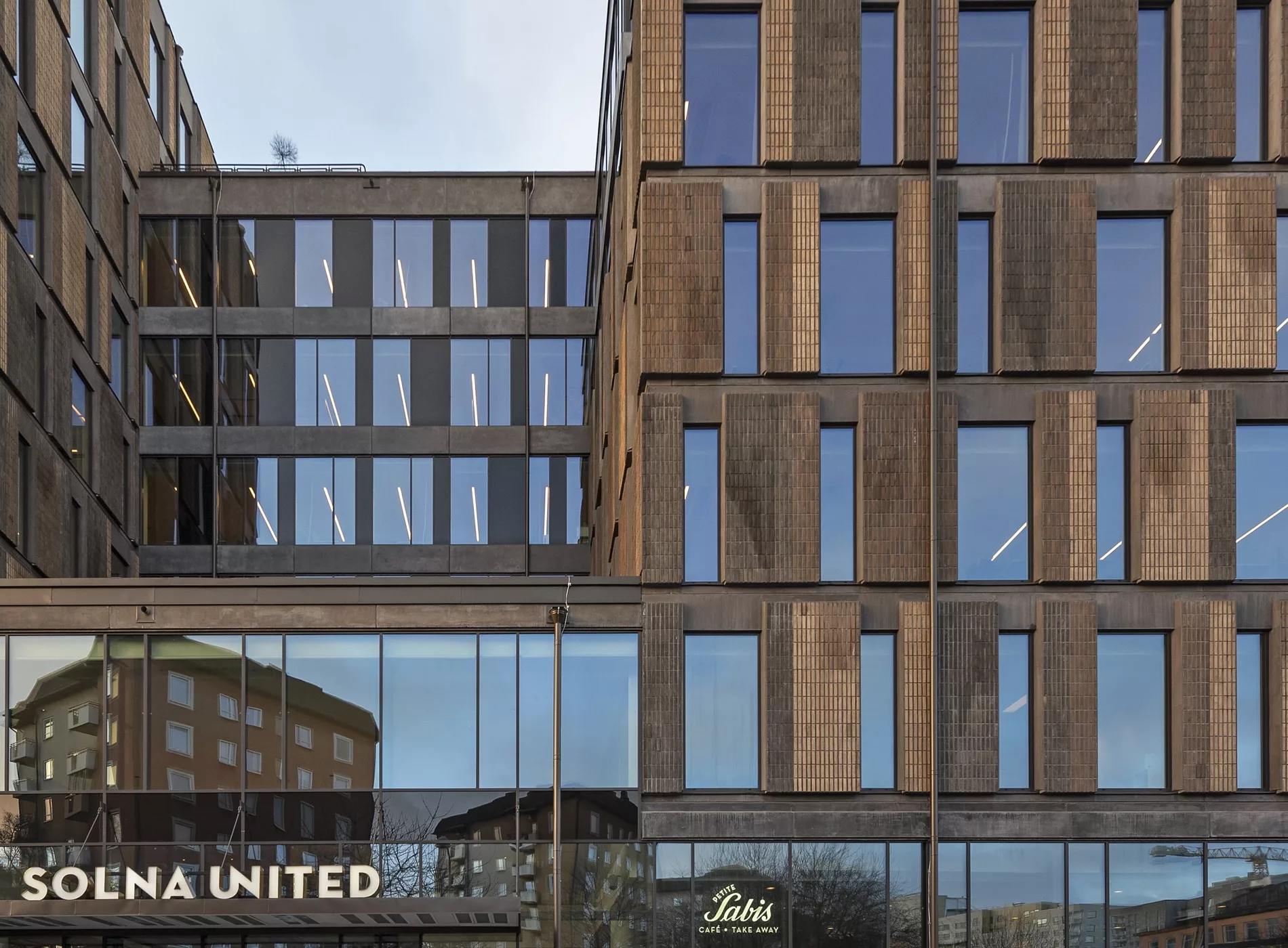 5. En modern kontorsbyggnad med stora fönster och tegelarkitektur, med texten "A HOUSE UNITED" synlig i nedre hörnet.