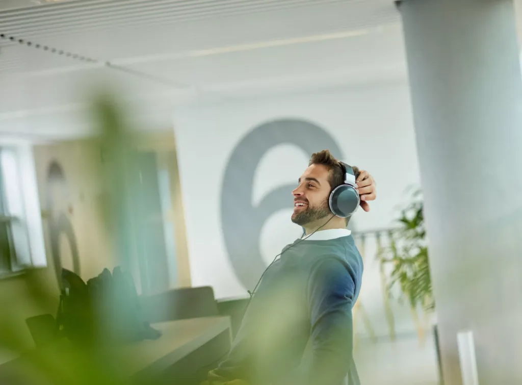 Man med hörlurar sitter vid ett skrivbord på ett kontor.