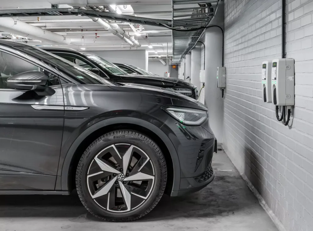 4. En svart bil parkerad inomhus med laddstation på väggen bredvid.