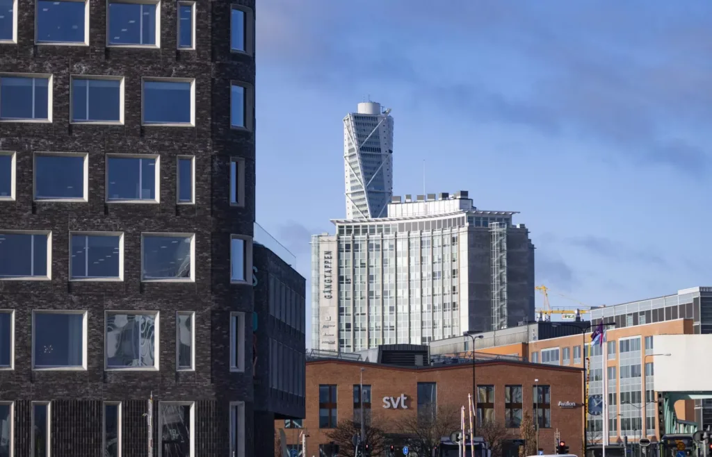 Turning Torso och andra byggnader syns mot en blå himmel i stadsmiljö.