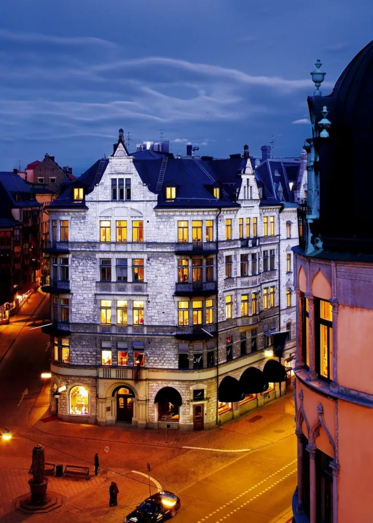 En historisk byggnad upplyst i mörker med detaljerad fasad och omgivande stadsgata.