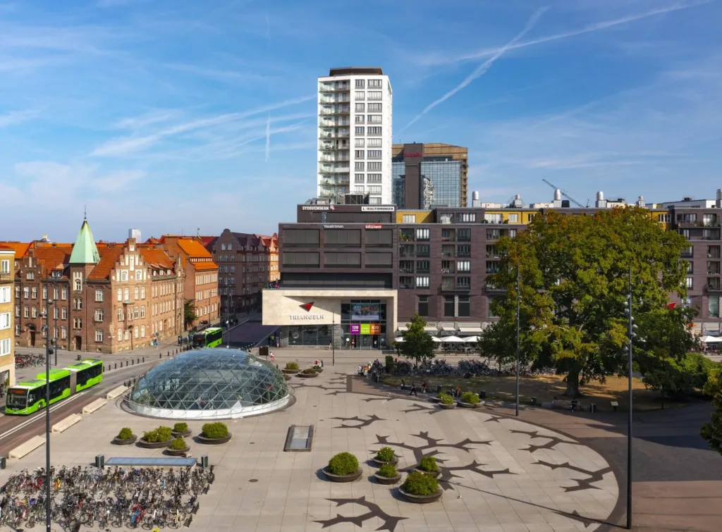 Triangeln-torget med en glaskupol, omgivande byggnader och skulpturer.