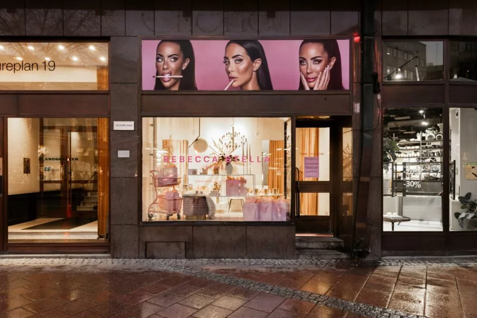 4. En butik med ett skyltfönster och en affisch av tre kvinnor ovanför ingången.