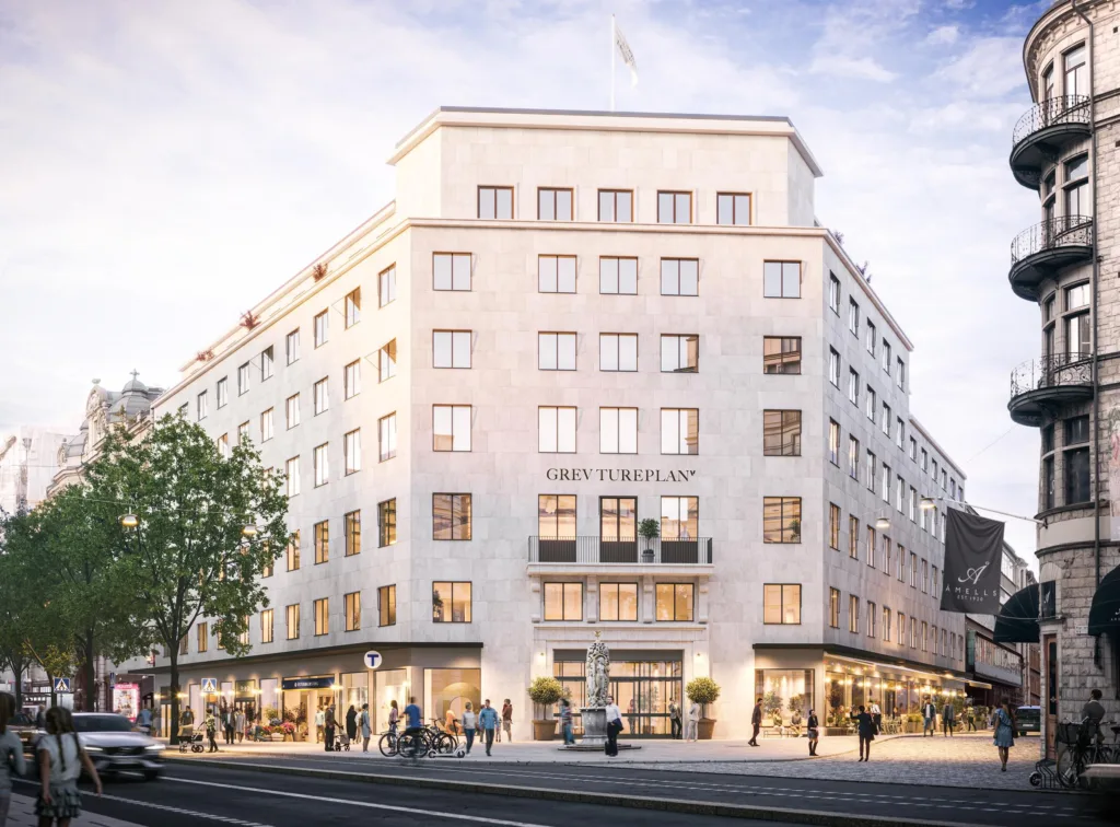 En ljus byggnad i klassisk stil med stora fönster och ett hotellnamn synligt på fasaden.