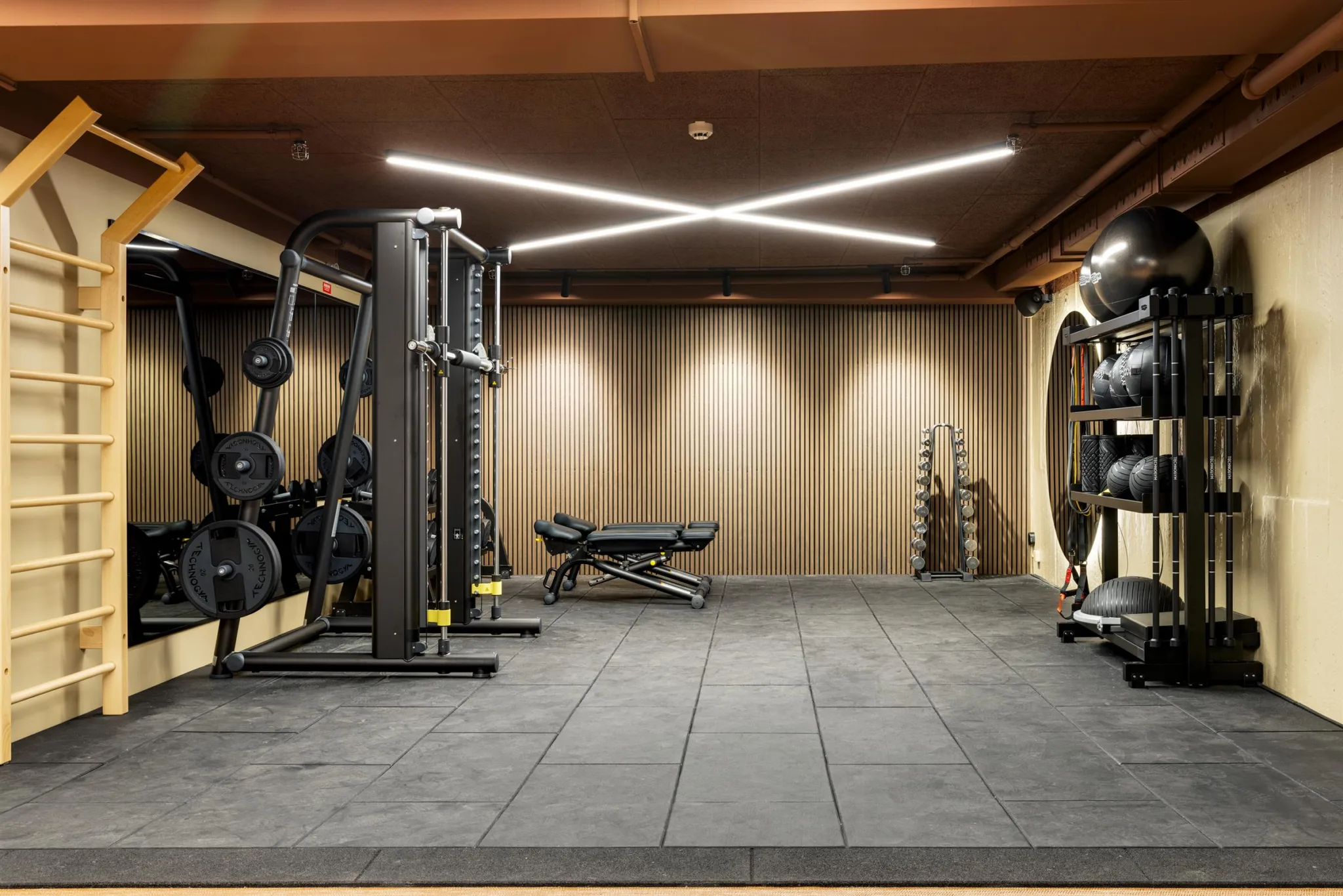 1. Ett gym med träningsutrustning, bänkpress och speglar på väggarna.
