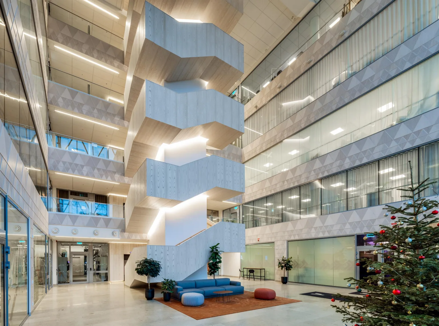 1. En modern byggnadsinteriör med en central spiraltrappa, omgiven av glasväggar och kontorsutrymmen.