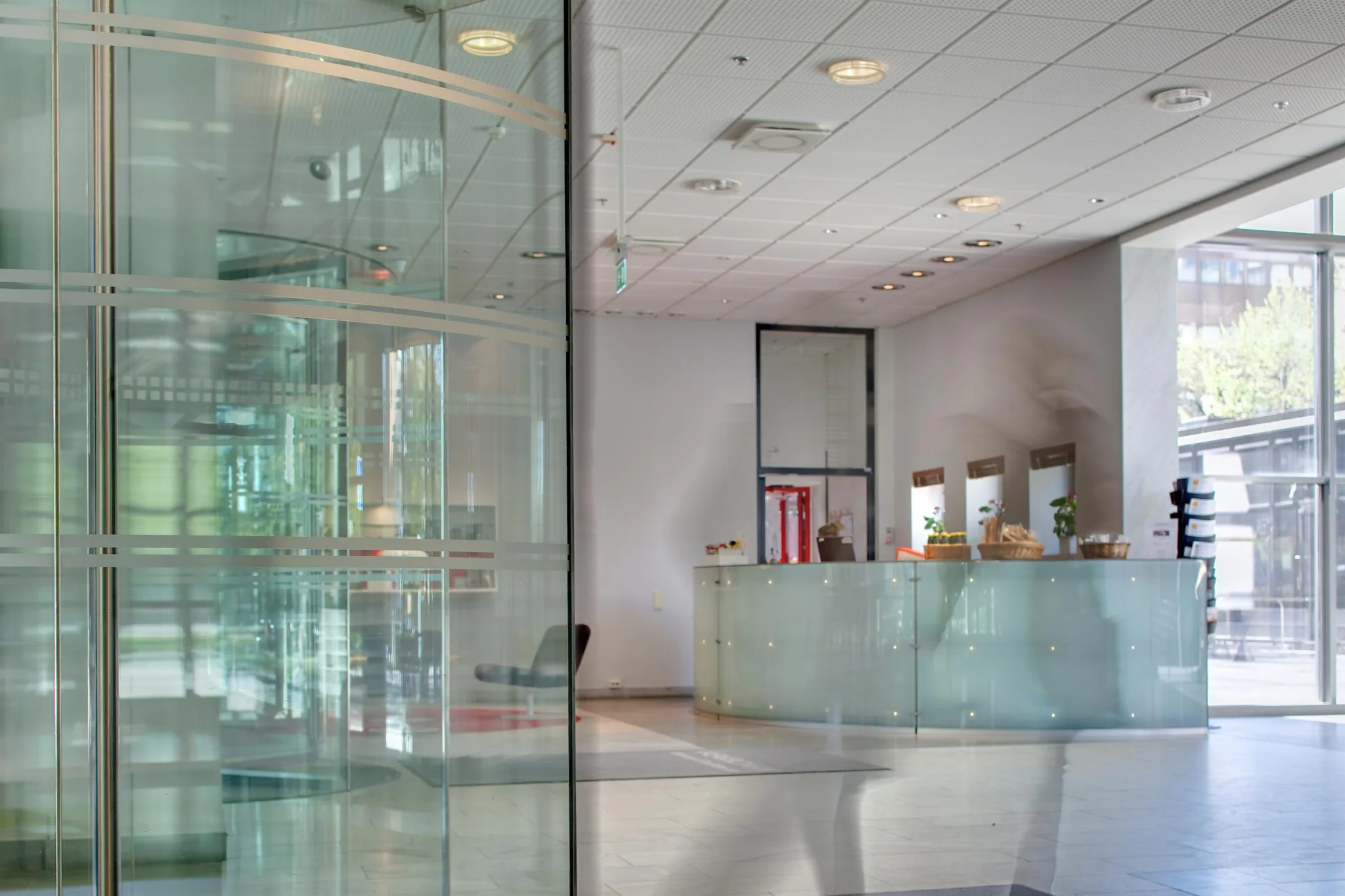 En reception med glasdetaljer och en disk, omgiven av speglande ytor och en modern inredning.