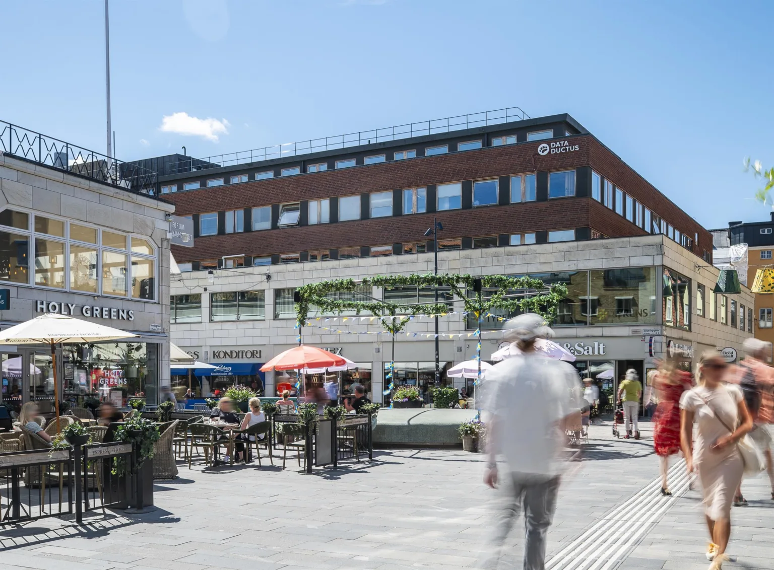 En utomhusservering med parasoller och ett tegelhus i bakgrunden.
