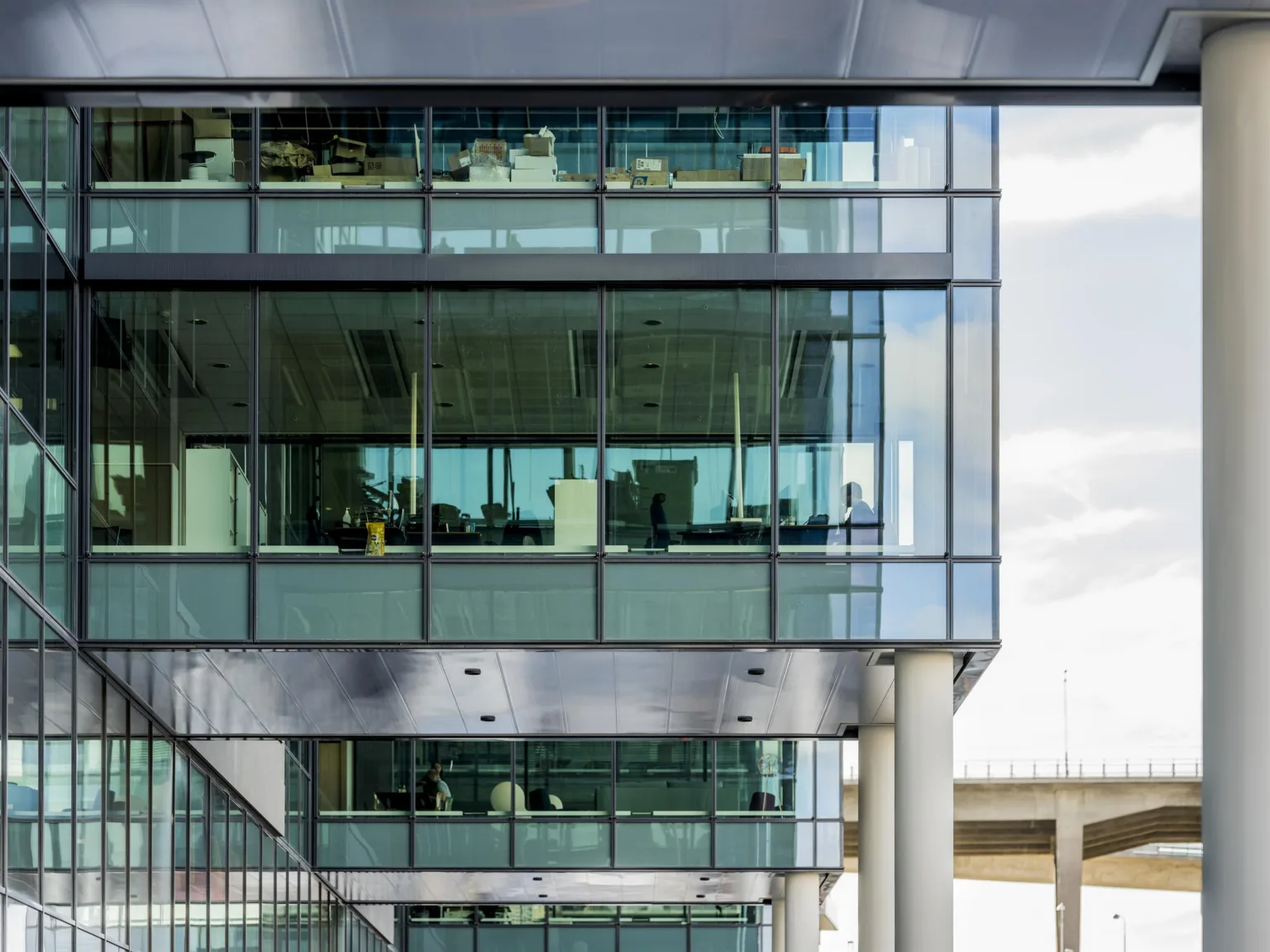 En modern byggnad med glasfasad som visar interiören och flera våningsplan.