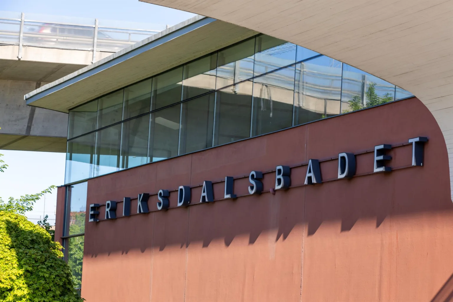 5. En byggnad med texten "Eriksdalsbadet" på en röd vägg och stora glasfönster ovanför.