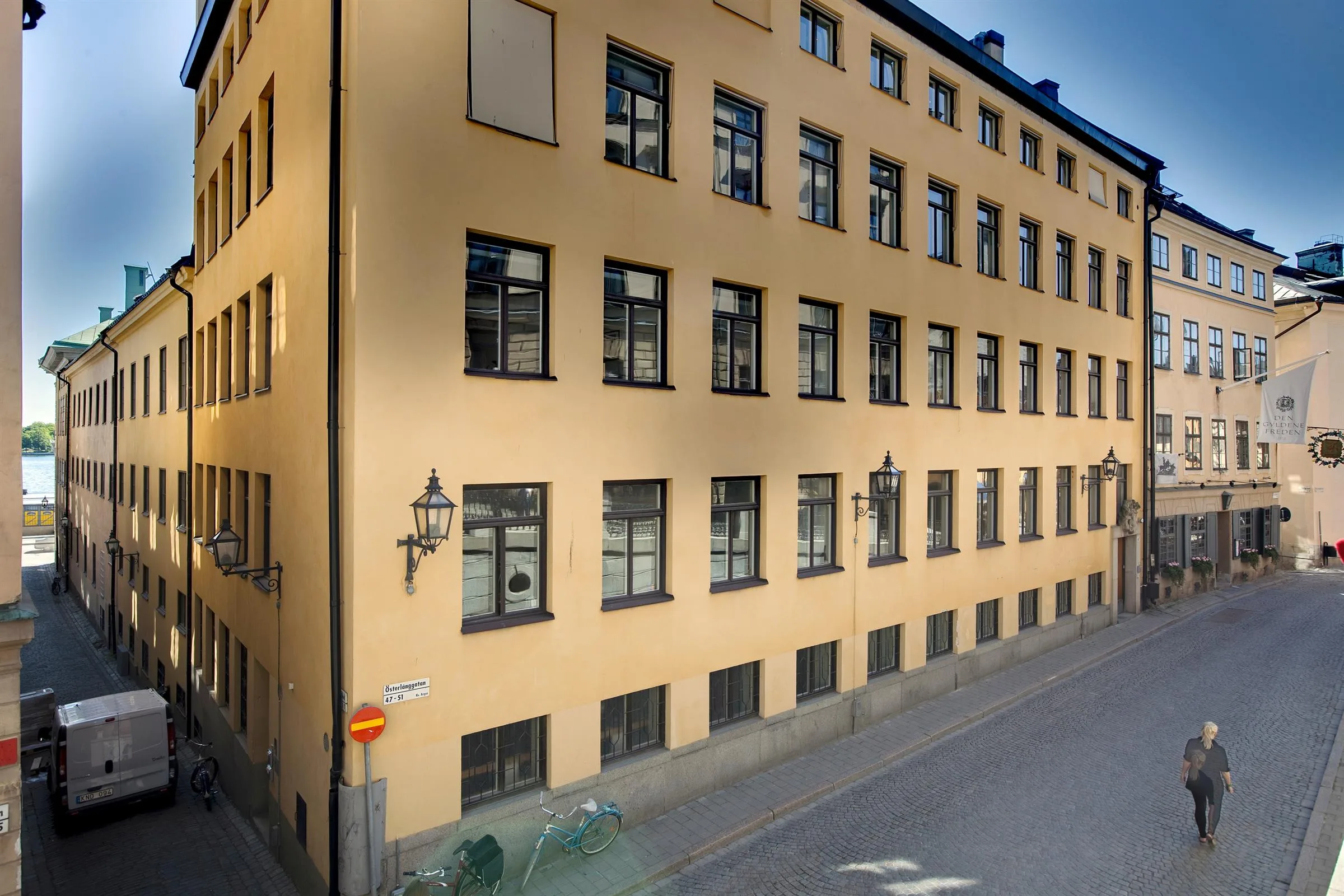 Gulfärgad byggnad med många fönster längs en sluttande gata.