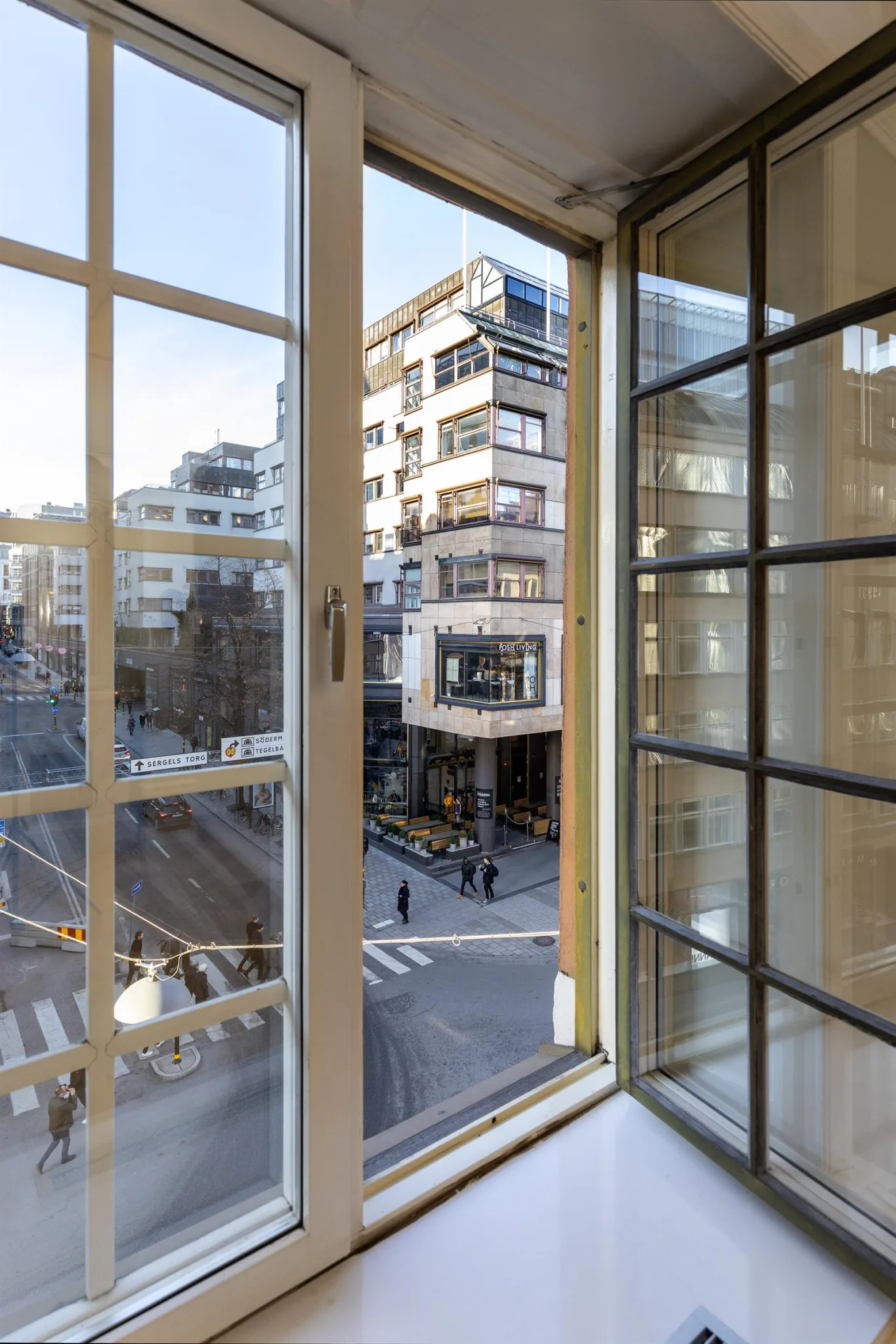 Fönster med spröjs som visar en stadsmiljö med moderna byggnader och en korsning.
