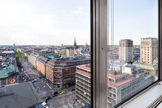 Utsikt över en stad från en hög byggnad, med kyrktorn och stadsbyggnader i fjärran.