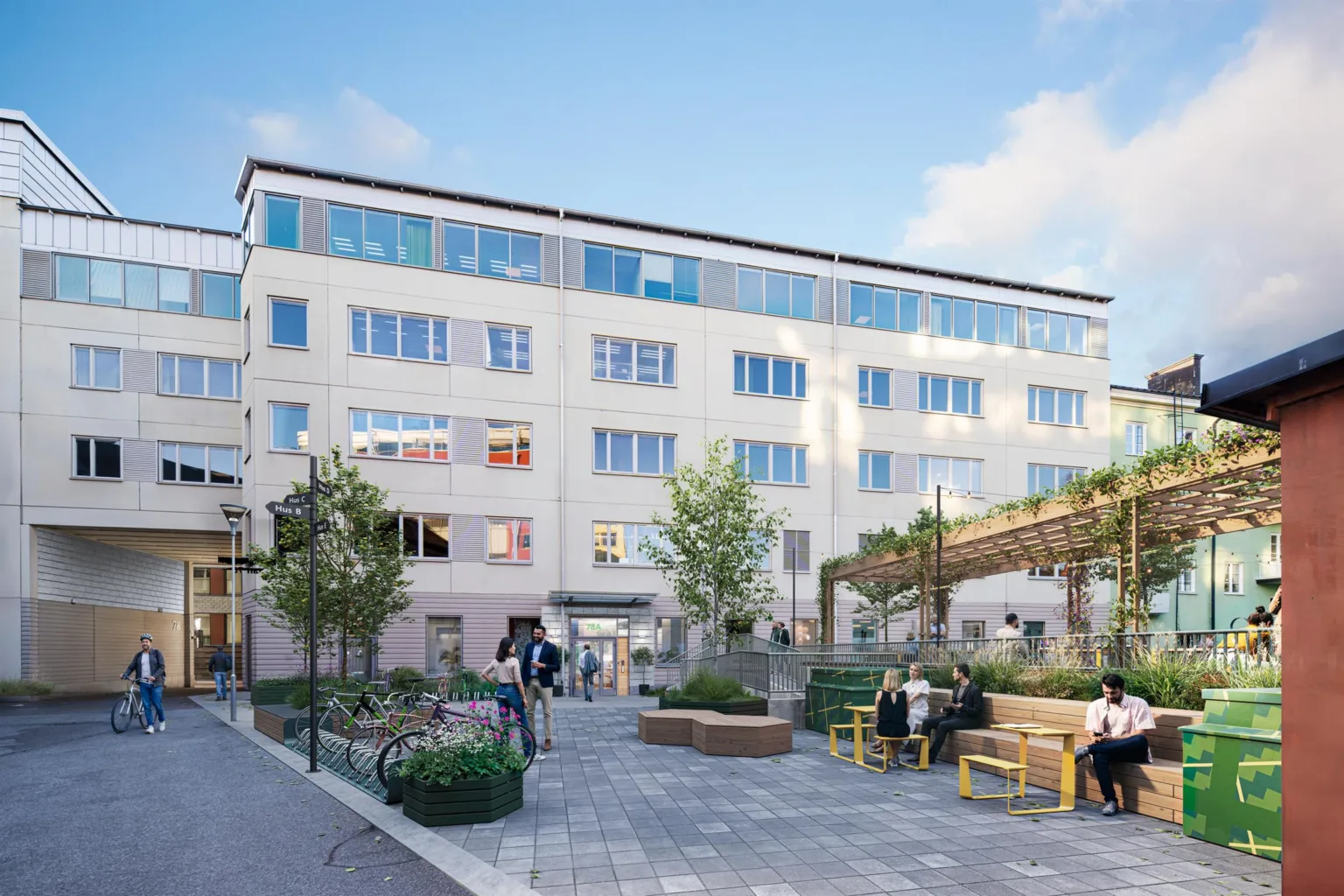 En byggnad med flera våningar och en utomhusgård med sittplatser och grönska.