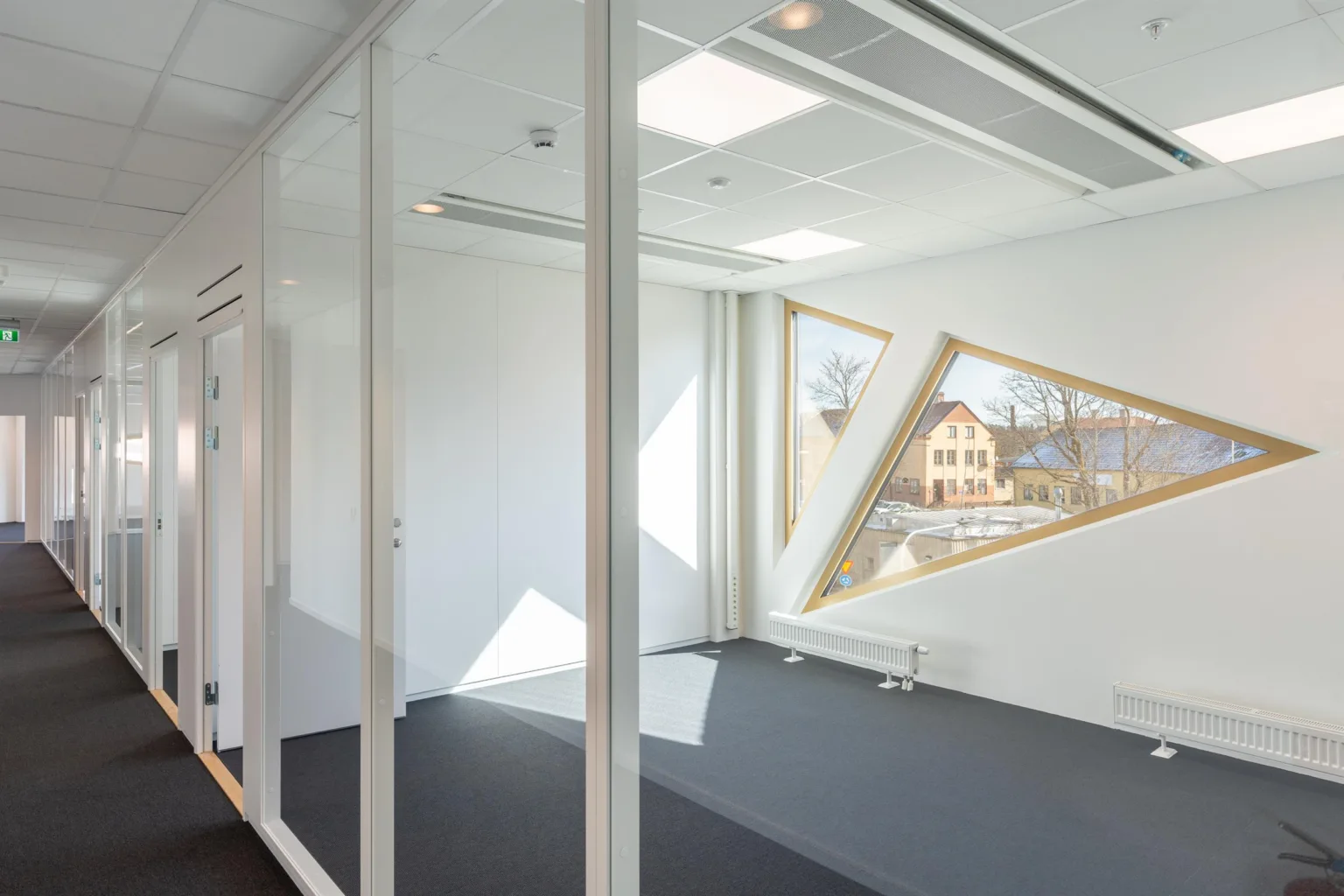 3. Ett ljust kontorsrum med geometriska fönster som visar utsikten utanför.
