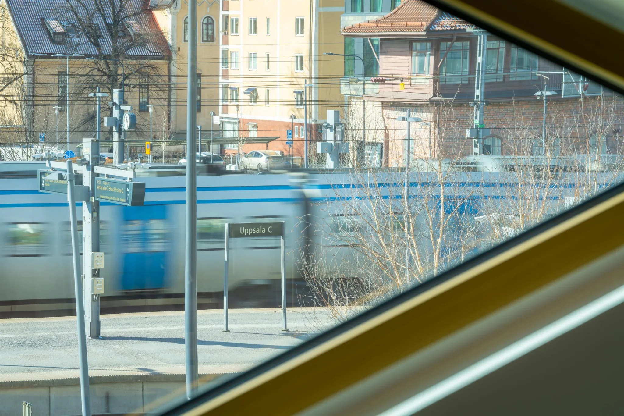 2. Ett suddigt tåg passerar utanför ett fönster med utsikt över byggnader och trä.