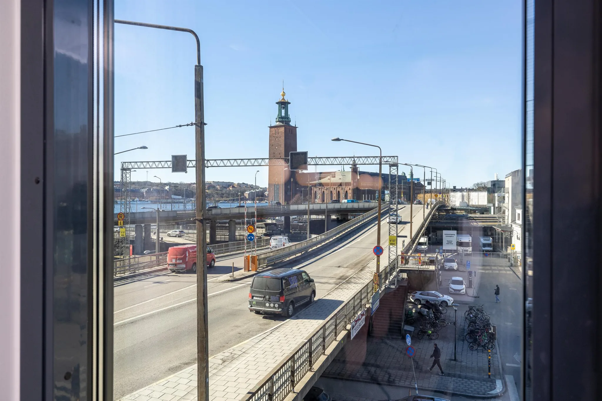 4. En stadsutsikt med en väg, bilar, gångtrafik och Stadshuset i bakgrunden under en klarblå himmel.