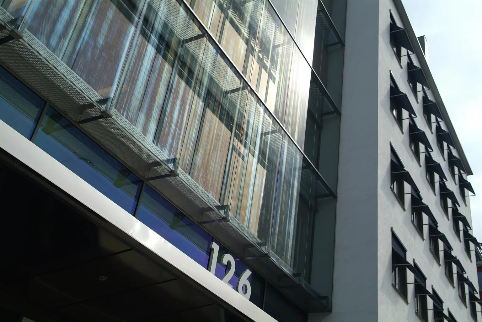 1. En byggnadsfasad med glaspartier och siffran "126" synlig nära en blå skylt.