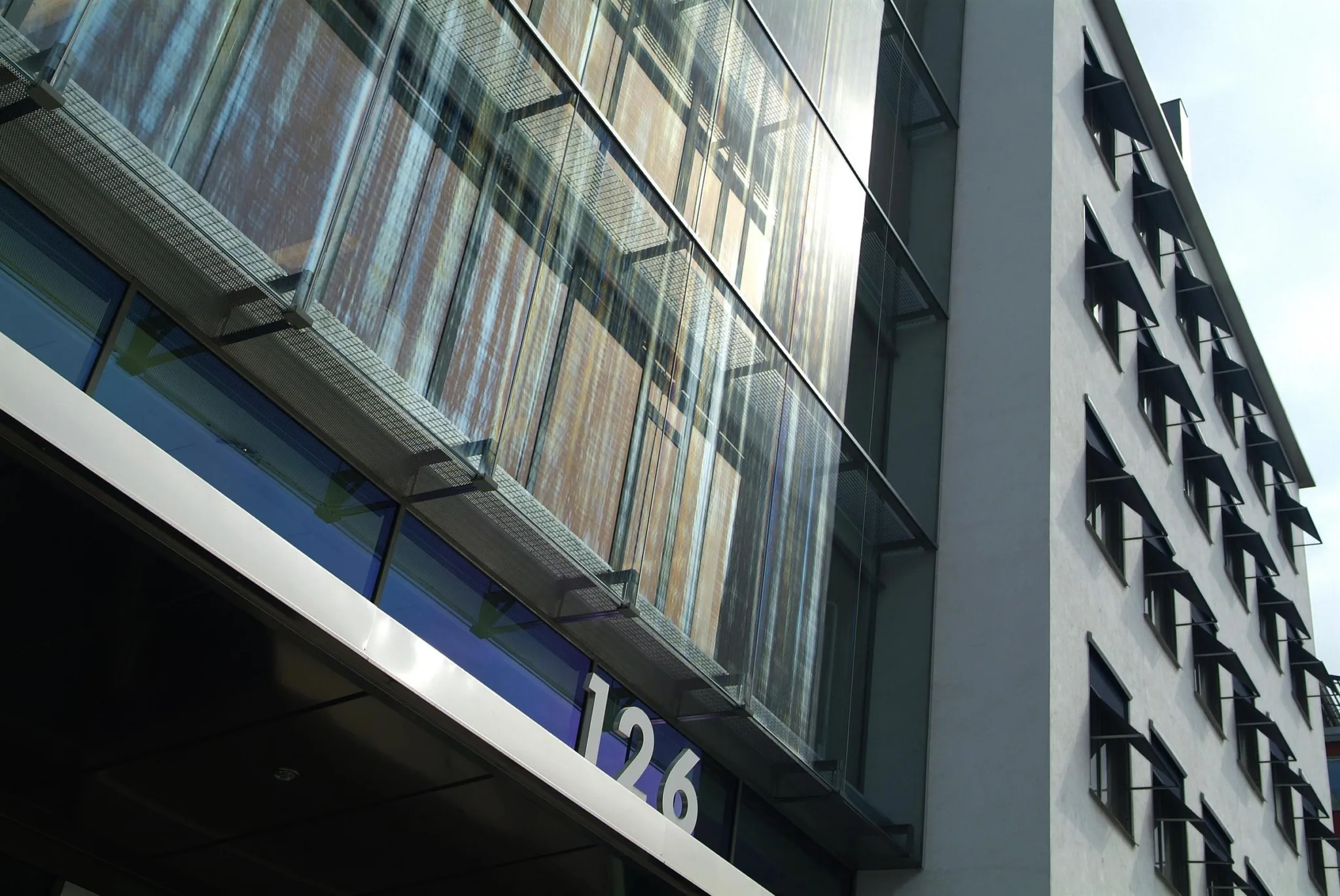 1. En byggnadsfasad med glaspartier och siffran "126" synlig nära en blå skylt.