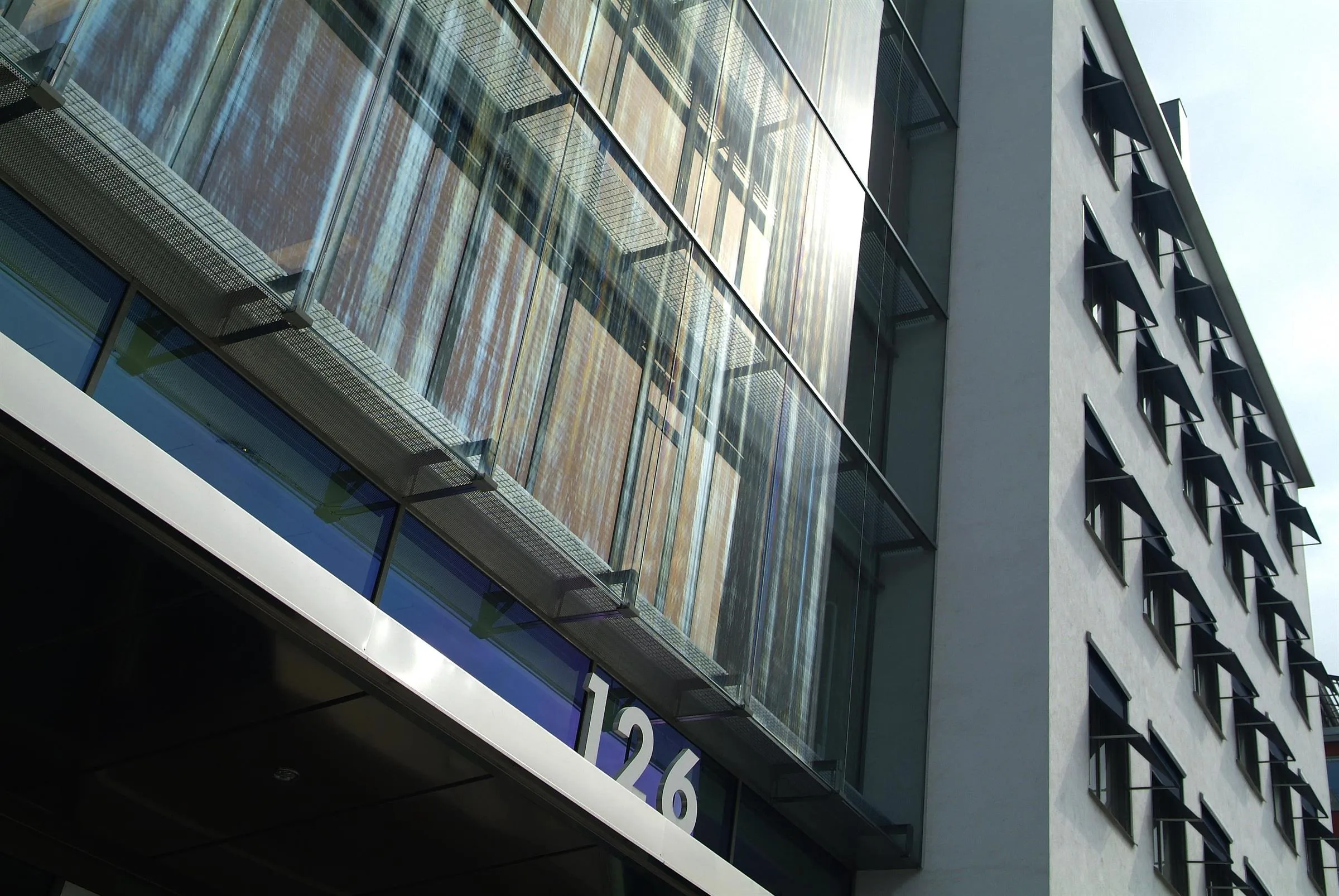 1. En byggnadsfasad med glaspartier och siffran "126" synlig nära en blå skylt.
