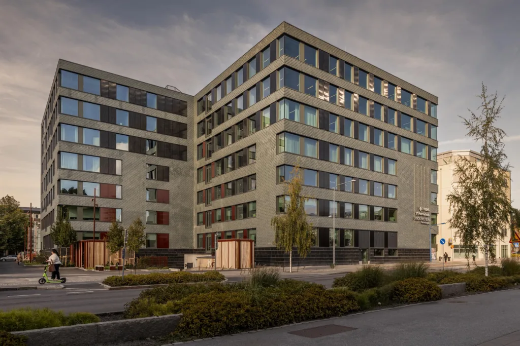 Modern byggnad med flera våningar, stora fönster och en innergård.